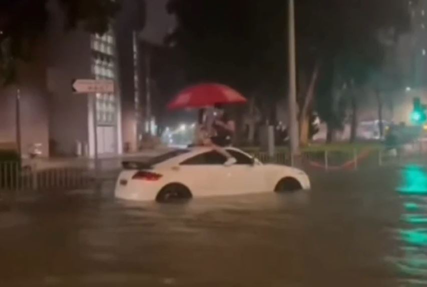 一對男女被迫爬上車頂避險，在飄浮在洪水中的車頂撐著紅色的雨傘對坐，狀甚浪漫。