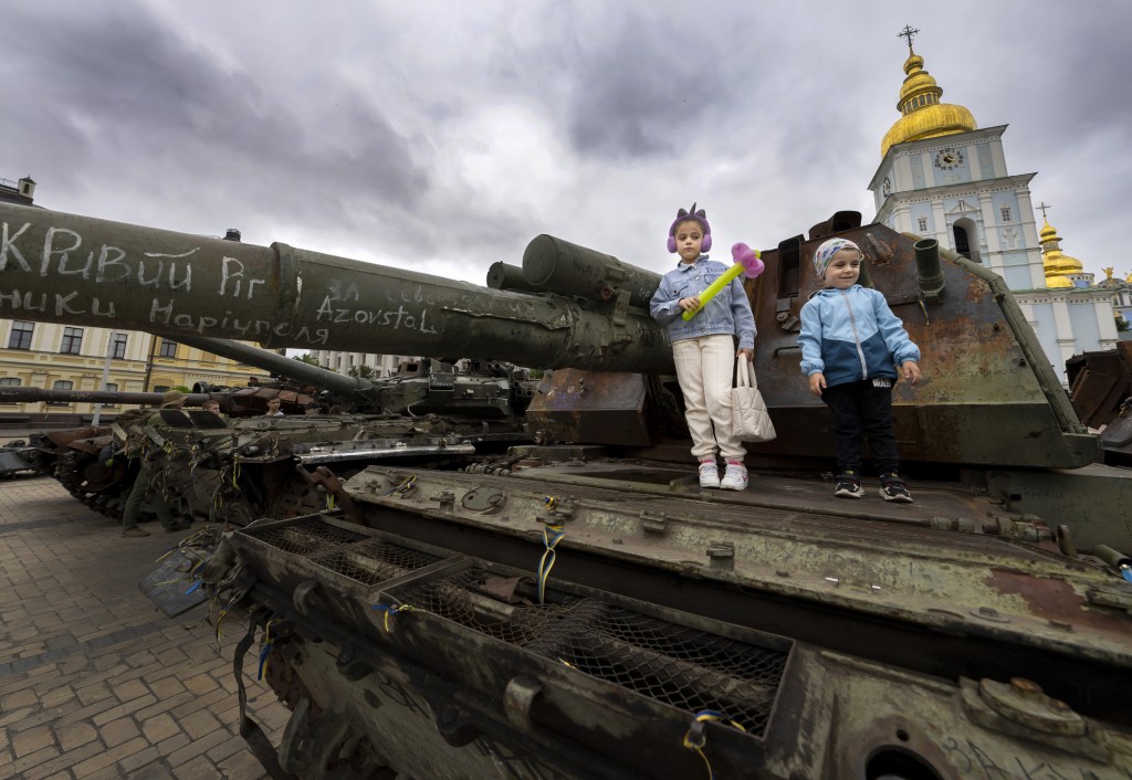 孩子们站在乌克兰基辅圣迈克尔广场烧毁的俄罗斯坦克上。路透