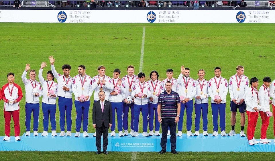 香港隊在「十五運會香港賽馬會盃七人制橄欖球比賽」奪得金牌，廖長江（前排左）頒獎予港隊運動員。