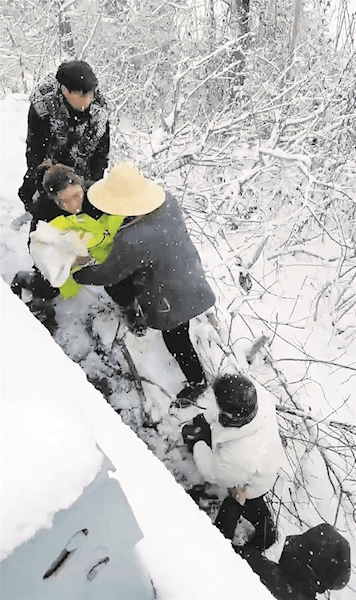 在大雪紛紛揚揚下，嬰兒包裹著路政工作人員穿的反光背心，由眾人轉離高架橋。