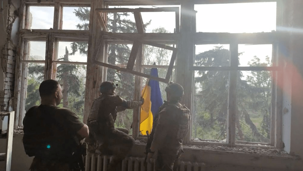 烏克蘭士兵們在一棟遭到轟炸過的建築升起國旗。路透