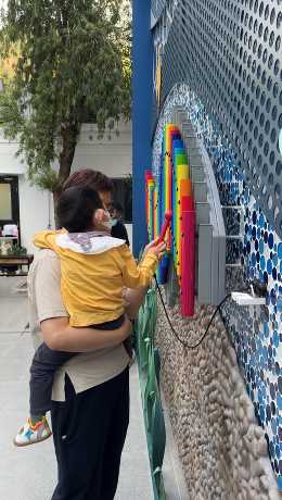  病人和家長一同在花園內的音樂設施遊玩。