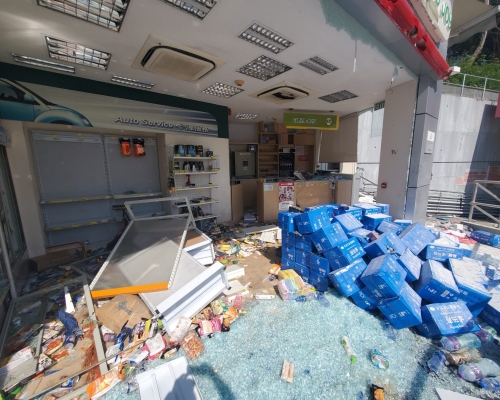 油站便利店貨物散落一地，有貨架被推倒，一地玻璃碎。