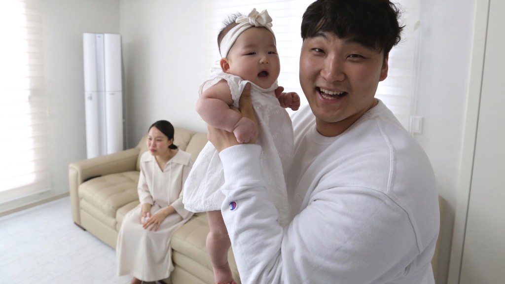 一名南韩爸爸抱着实际月龄3个多月大的女儿，在虚岁算法下她已「2岁」。 美联社