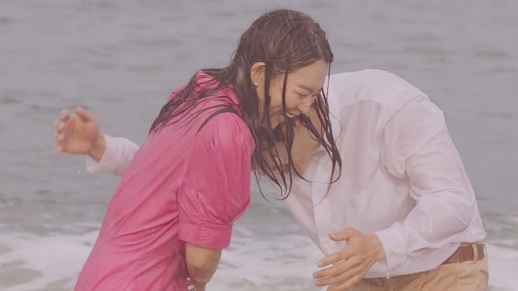 二人在沙灘淋雨嬉戲。