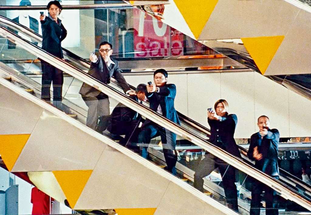 杜琪峯在《鎗火》善用荃灣廣場的電梯、噴水池和柱子，拍攝兩派殺手對峙、駁火，風格冷峻懾人。