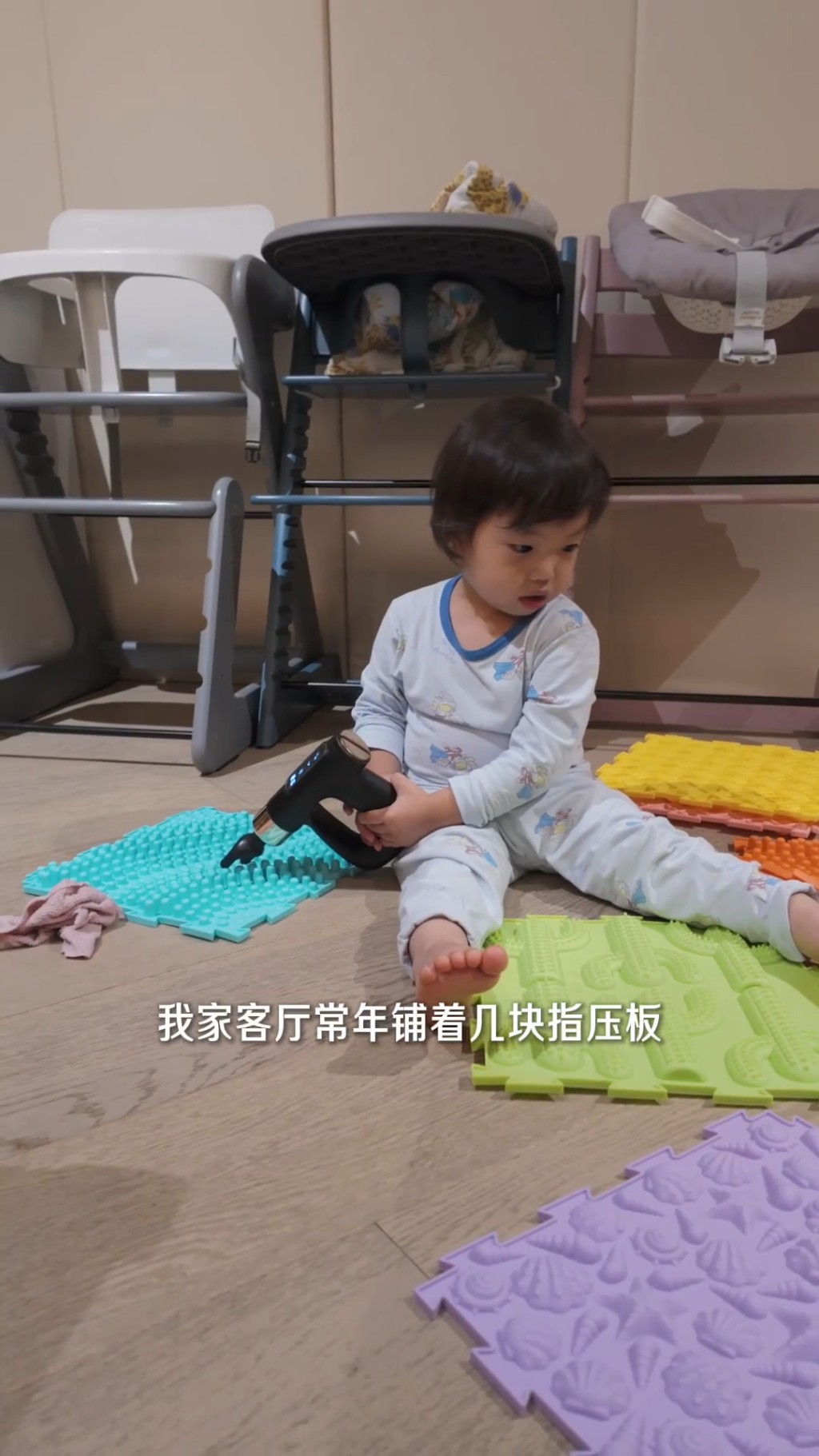 「袁咕碌」坐在指壓板上，探索不同的玩具，但他正在玩按摩槍。
