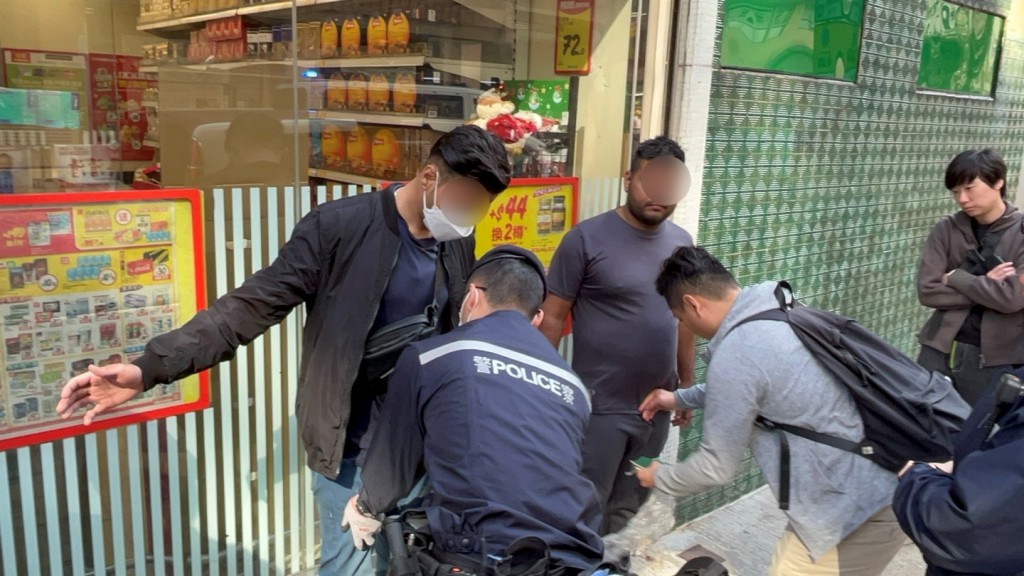 警員在寶文街1號對開截查及帶走兩名非華裔男子。楊偉亨攝