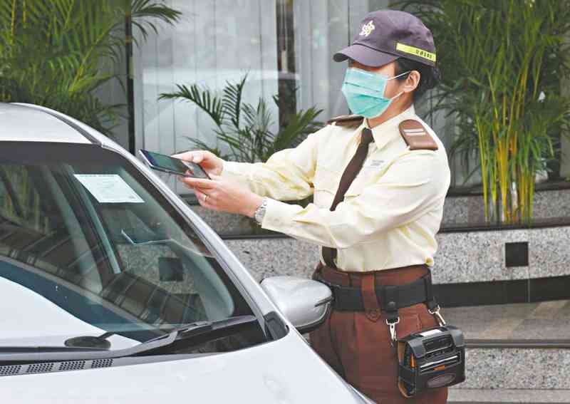 交通督導員示範掃描車輛牌照上的二維碼。香港警察圖片
