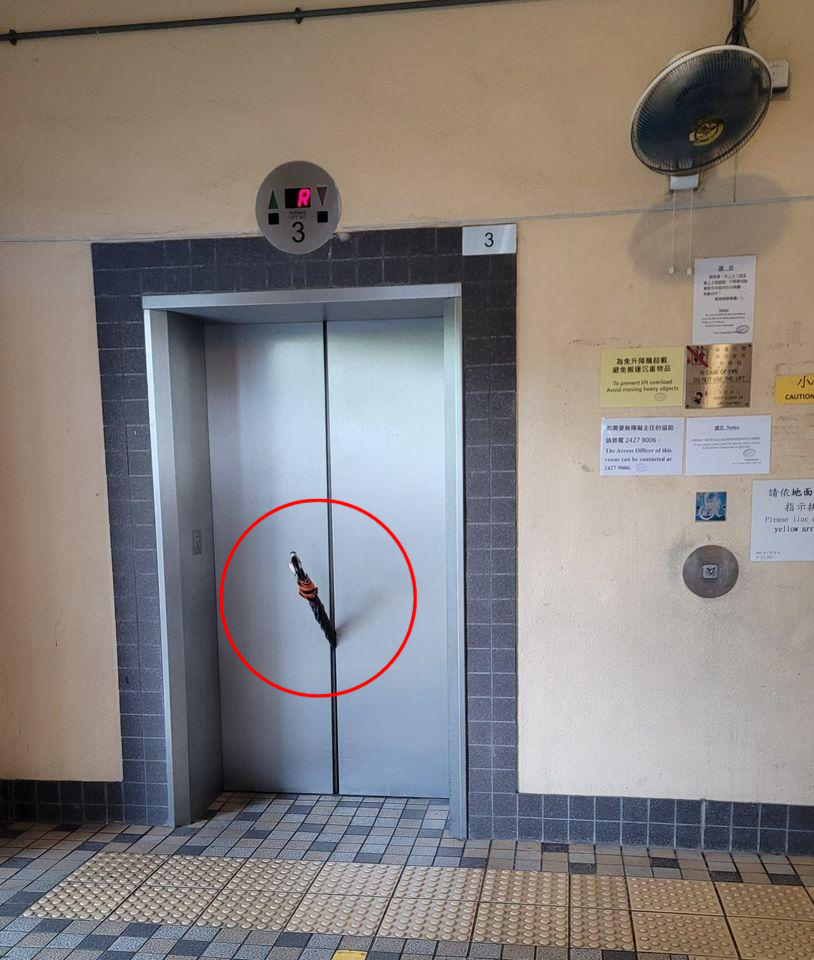 一把雨伞被葵涌邨的电梯门牢牢夹实。