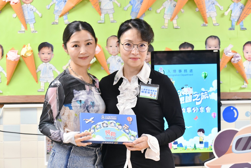 衛詩雅與入境處助理處長（個人證件）楊素英一同向學生派發《阿邦的夢想國之旅》兒童繪本及「阿邦」公仔等。