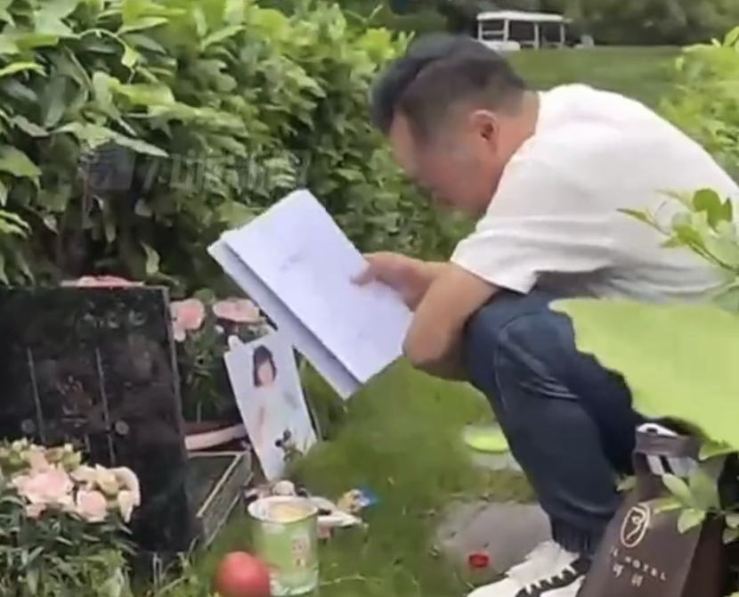 女童父親陳長江手拿判決書到墓地悼念女兒。