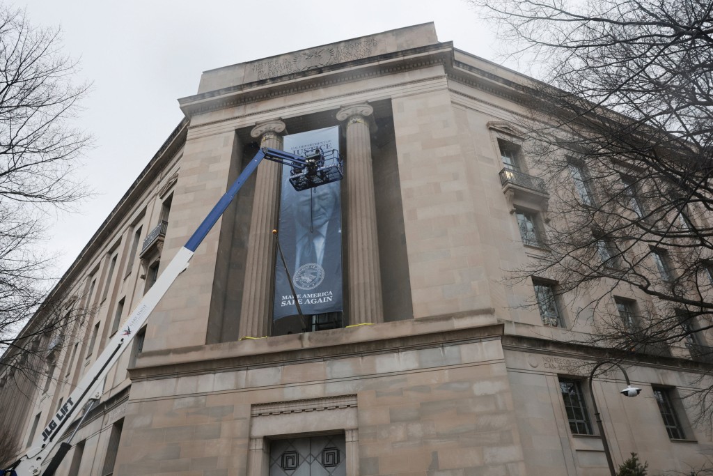 工人使用起重機懸掛橫幅的照片。路透社