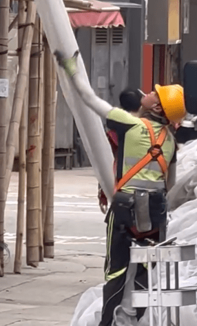 在柴灣長匯工業大廈外，今日仍有工人在拆除棚網時一邊食煙一邊拆網。興華茶餐廳IG影片截圖