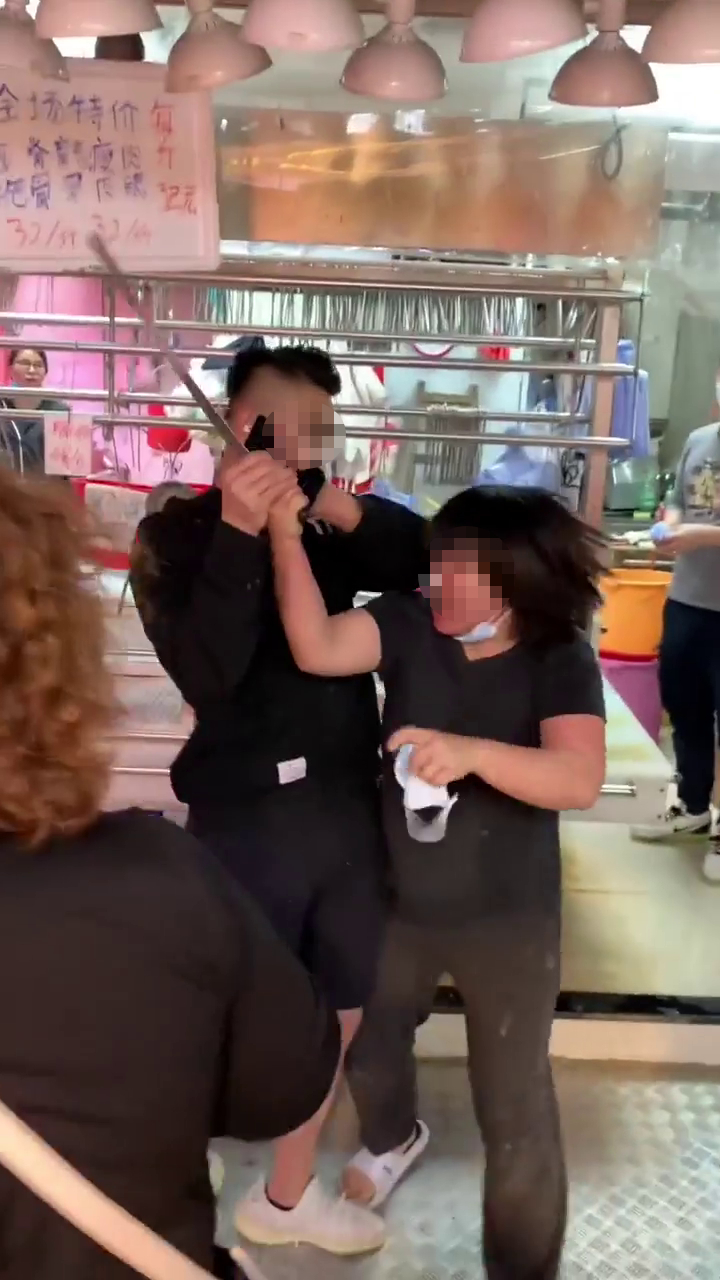 黑衫男已随即上前，按住女菜贩的手试图抢走西瓜刀。「香港江湖日报」FB网片