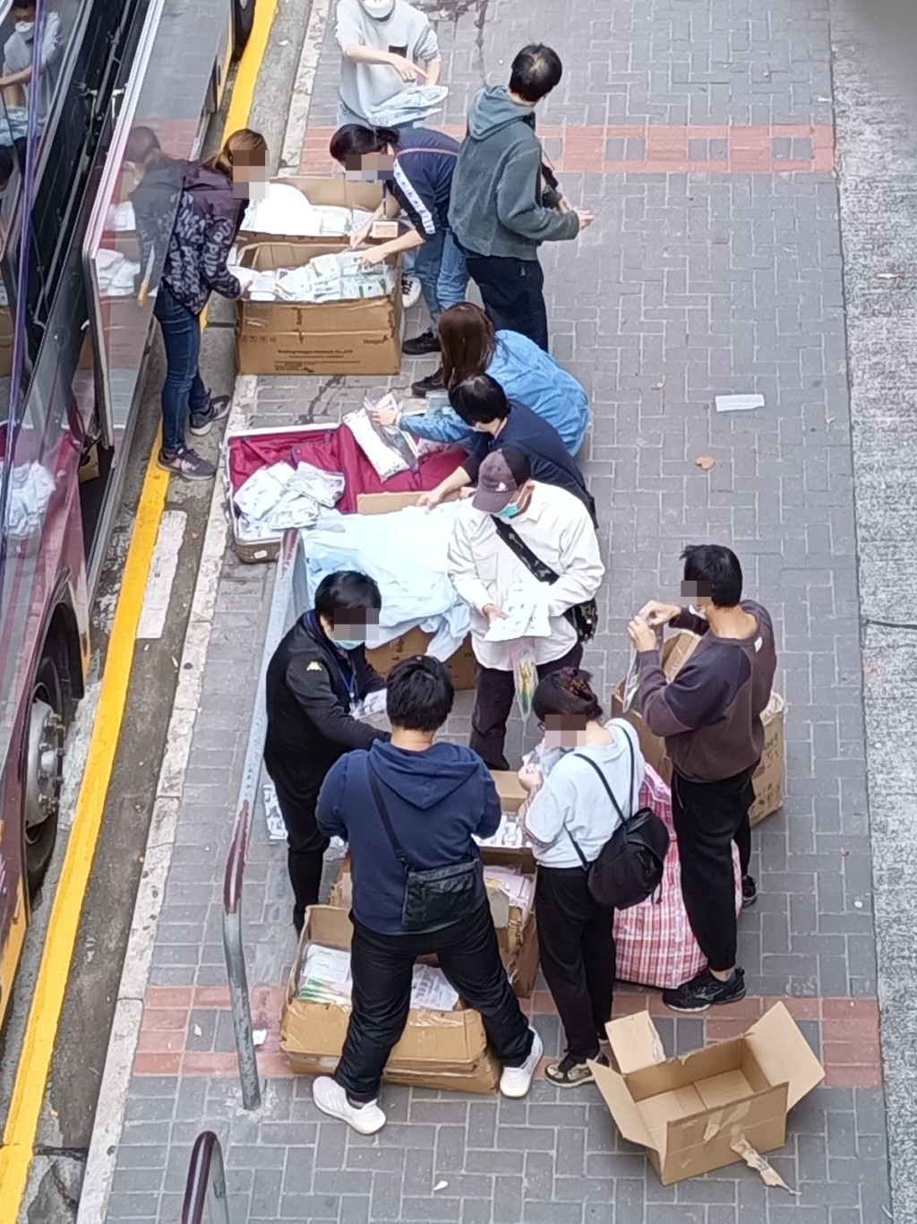 一批人在街頭整理快測包惹來分銷疑雲，但有網民指為政府外判工整理防疫物資包。K Kwong專頁圖片