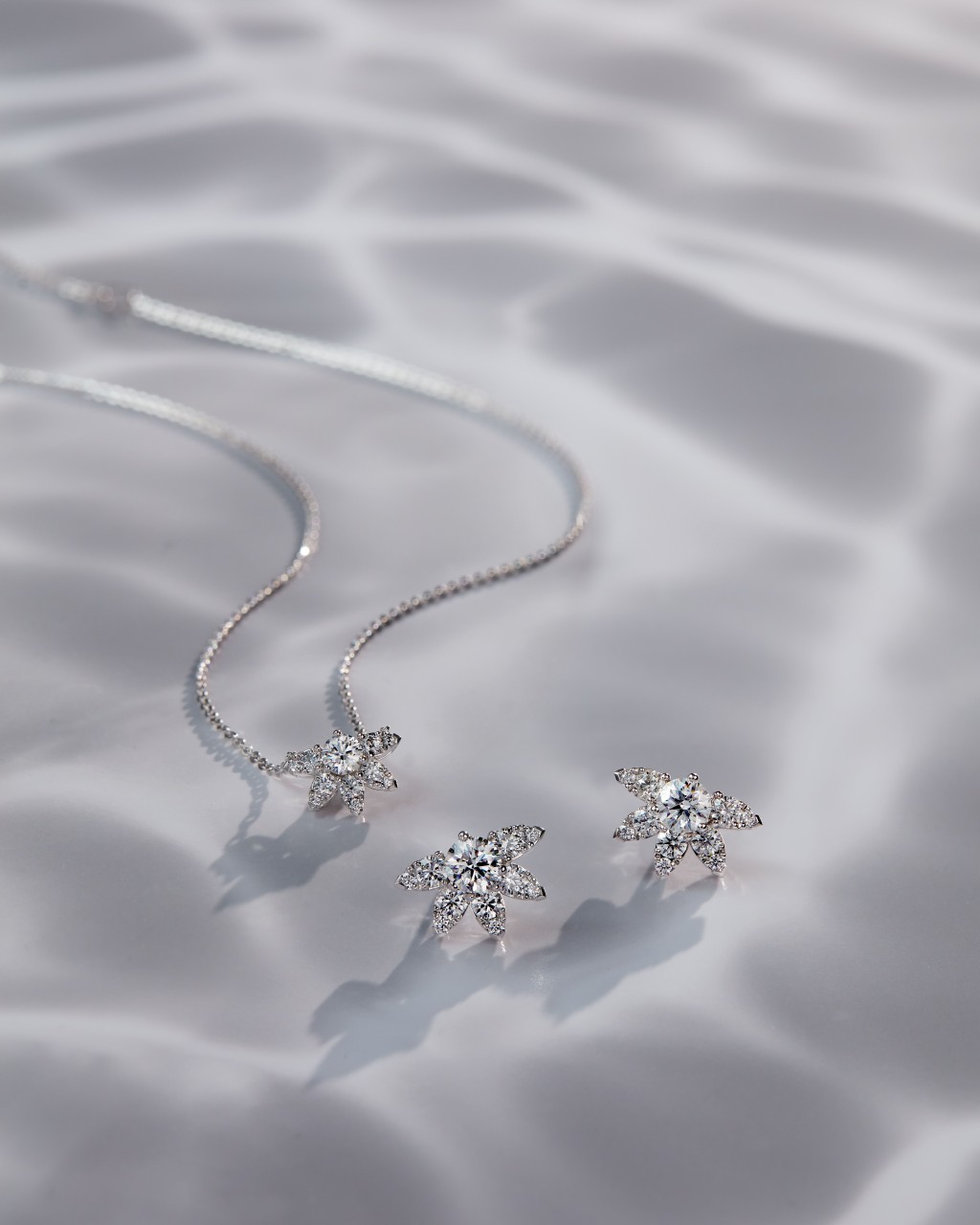 Aerial Sunburst鑽石耳環（大號）及項鏈，飾以欖尖形和梨形鑲嵌鑽石，恍如盛放的鮮花。耳環的周邊鑽石花瓣部分可拆下，作單顆圓鑽款式佩戴。