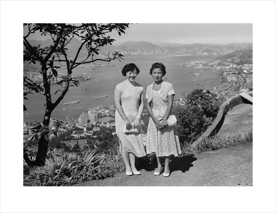 兩名衣着優雅的女士在山頂拍照留念，山下是中環市區。（黑白圖片）