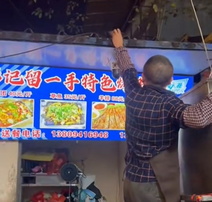 烤鱼店老板将鱼内脏放上屋簷，吸引猫咪到来。