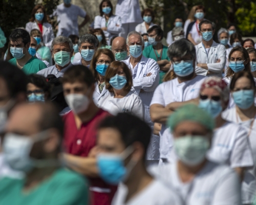 西班牙大批前線醫護為一名感染新冠肺炎殉職的外科主任默哀1分鐘。AP圖