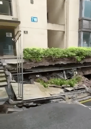 重庆市万州锦绣江南的一栋住宅楼旁道路下陷，露出地基。