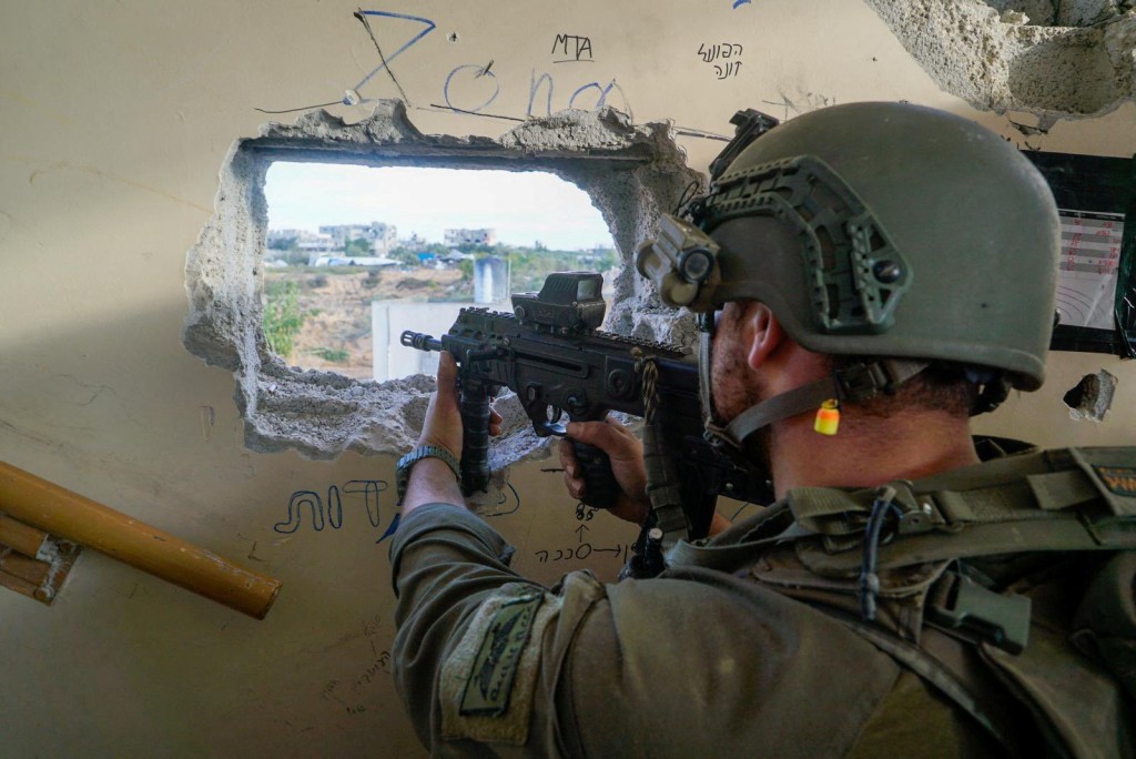 一名以色列士兵在加沙地带行动时用武器对准敌方。 路透社