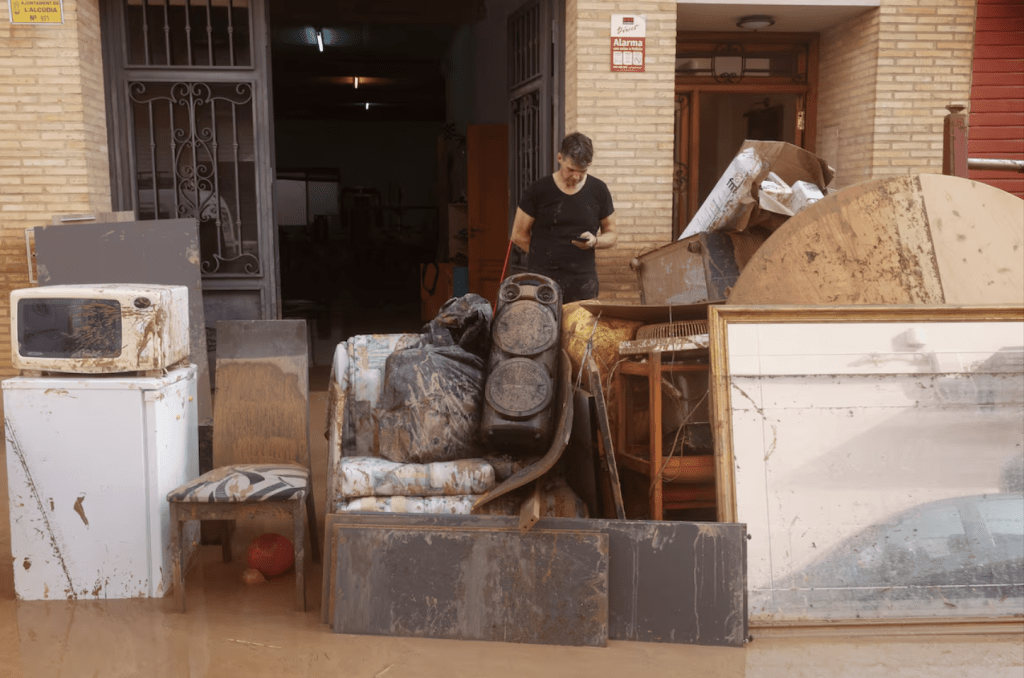 2024 年 10 月 30 日，西班牙巴倫西亞地區的拉阿爾庫迪亞，暴雨引發洪水，一名男子在泥漿覆蓋的街道上檢查手機。路透社