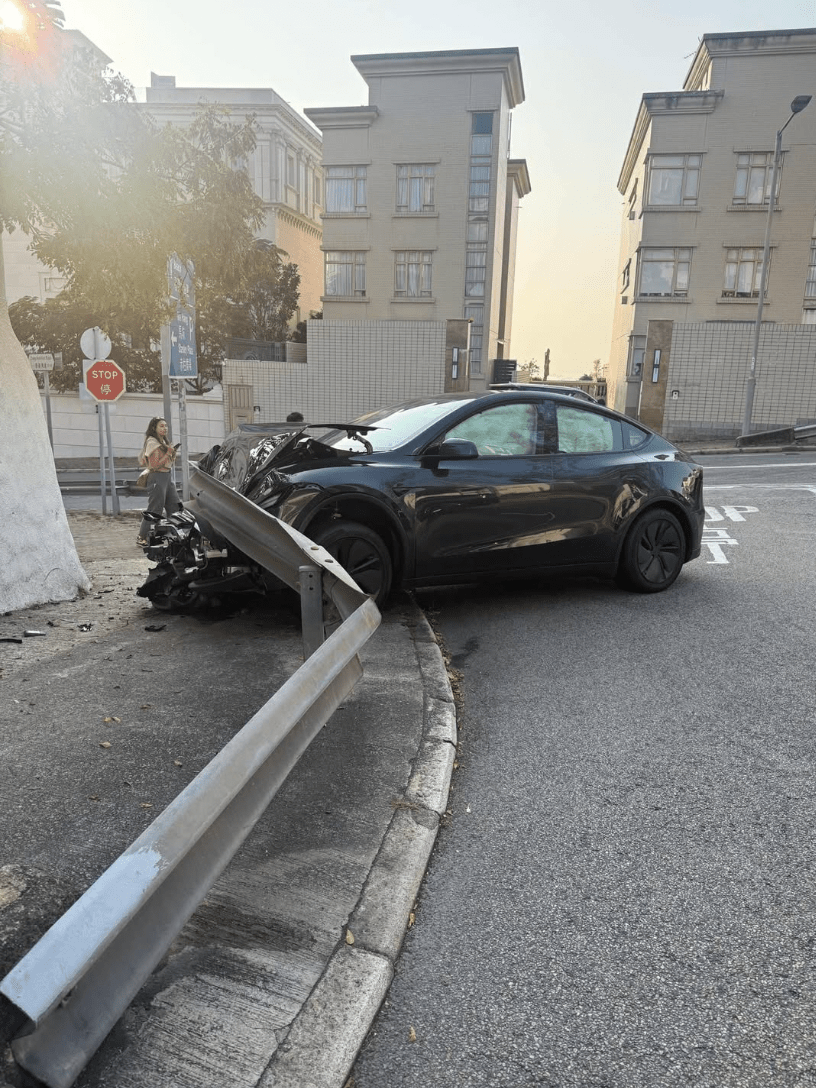 涉事Tesla其後剷上行人路，車頭嚴重損毀，零件碎片散落一地，車內安全氣袋彈出。fb@馬路的事討論區
