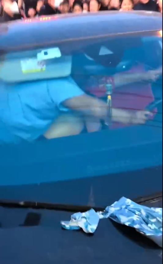 警員用身體為女事主遮擋身體，再用紅布裹身，護送她離開。影片截圖