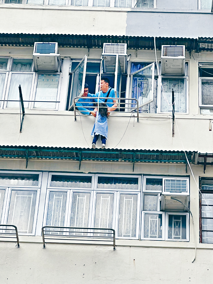 兩名男街坊合力將頭部卡於晾衣架的女童拉入屋內。 