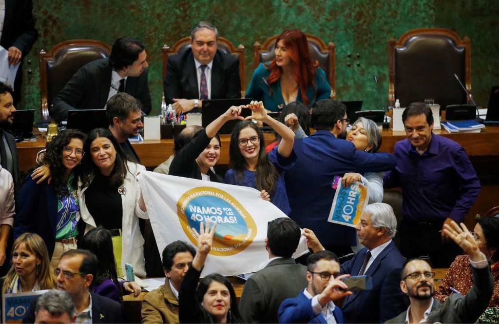 智利劳工部长贾拉（Jeannette Jara，中排右二）与其他部长庆祝每周工时逐步减至40小时的法安通过。路透社