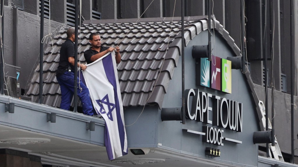 南非开普敦民众在建筑物顶部拆除以色列旗，以示支持巴勒斯坦人。 路透社