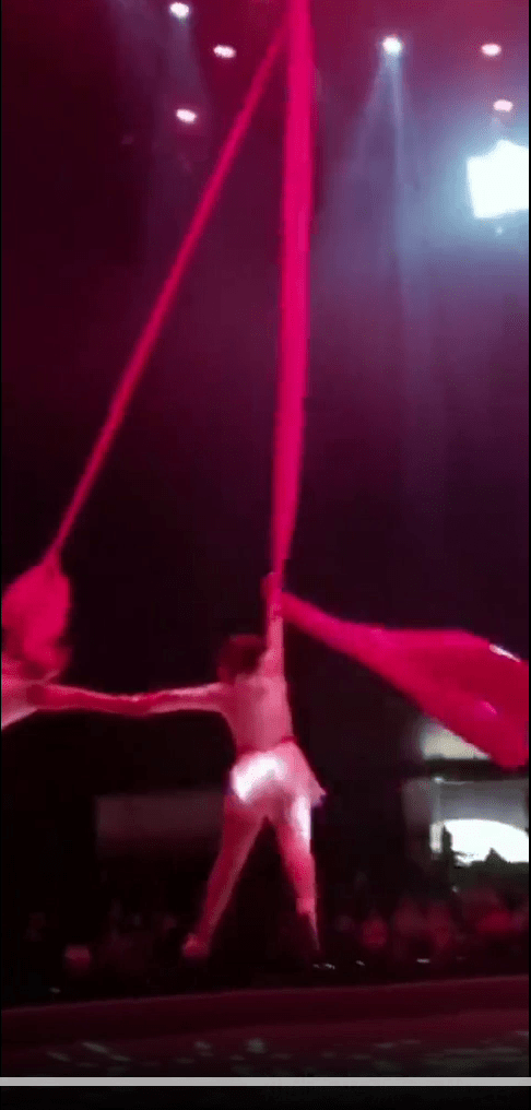 一男一女的杂技员利用红绸布，表演俗称绸吊的空中舞。