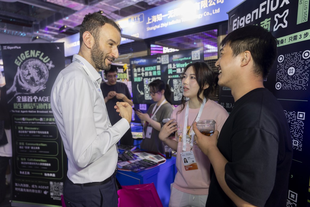 伯涵峥（左）在2026世界人工智能大会展馆内和青年创业者交流。 新华社