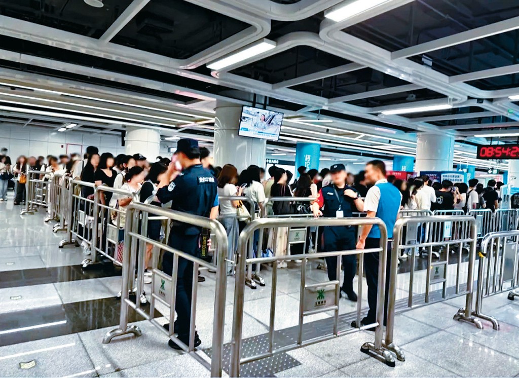 排隊安檢的乘客打蛇餅，地鐵人員設置鐵欄。