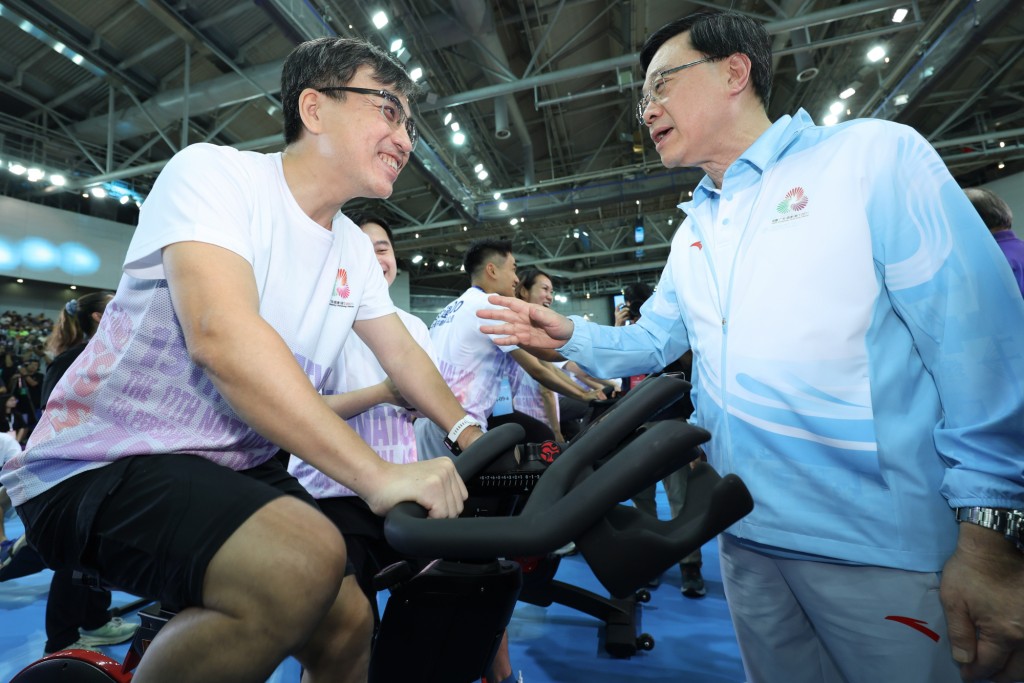 特首李家超（右）為參加「全運100全民共創百萬公里大挑戰」衝刺的馬會義工隊成員打氣。