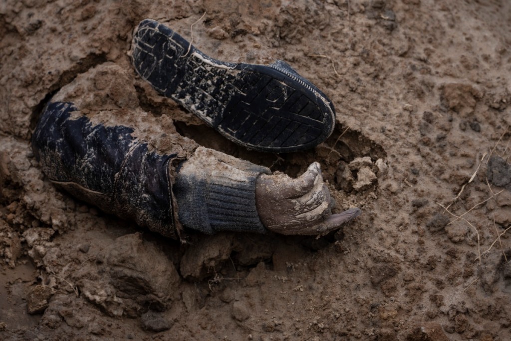 有平民被埋在泥下只露出一隻手。AP