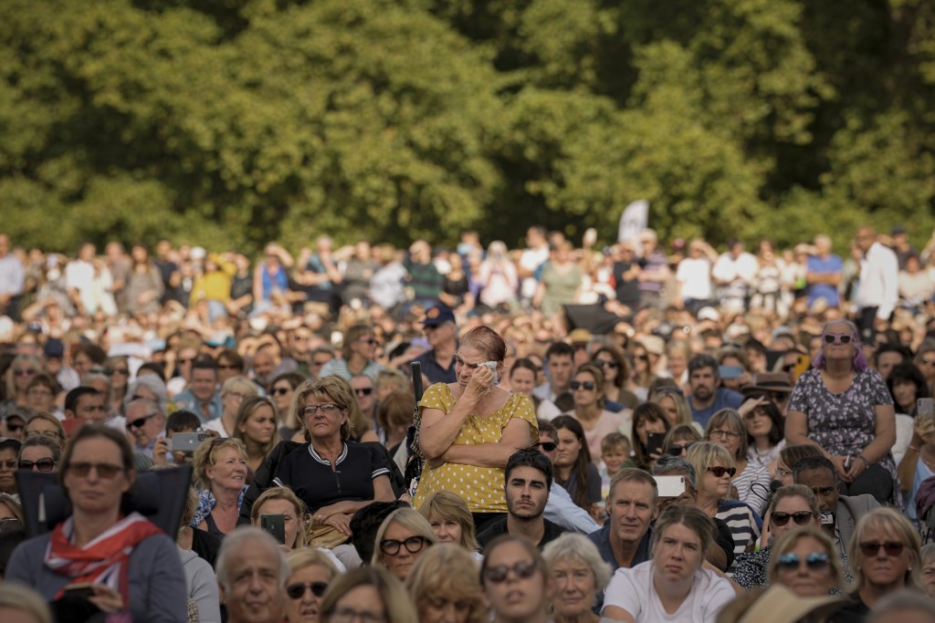 一名婦女與坐在倫敦海德公園的人們一起擦眼淚。AP
