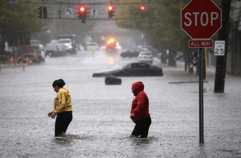 9月29日，紐約市郊區威徹斯特縣馬馬羅內克，居民在水深過膝的積水中行走。路透社