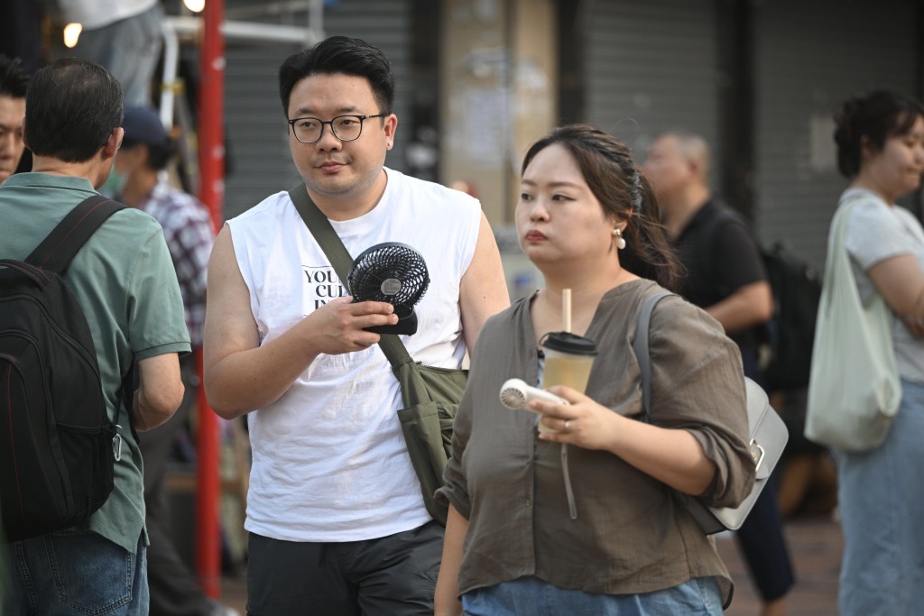 天氣炎熱,市民出街人手一把手提風扇。 天氣炎熱,市民出街人手一把手提風扇。