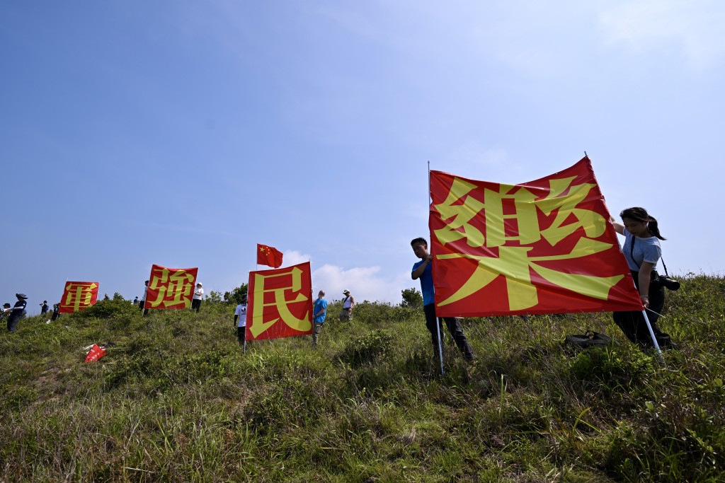 有市民於玉桂山頂上舉起自製的「軍強民樂」旗幟,表示是回應山東艦進港時甲板上的「國安家好」字句。劉駿軒攝 有市民於玉桂山頂上舉起自製的「軍強民樂」旗幟,表示是回應山東艦進港時甲板上的「國安家好」字句。劉駿軒攝