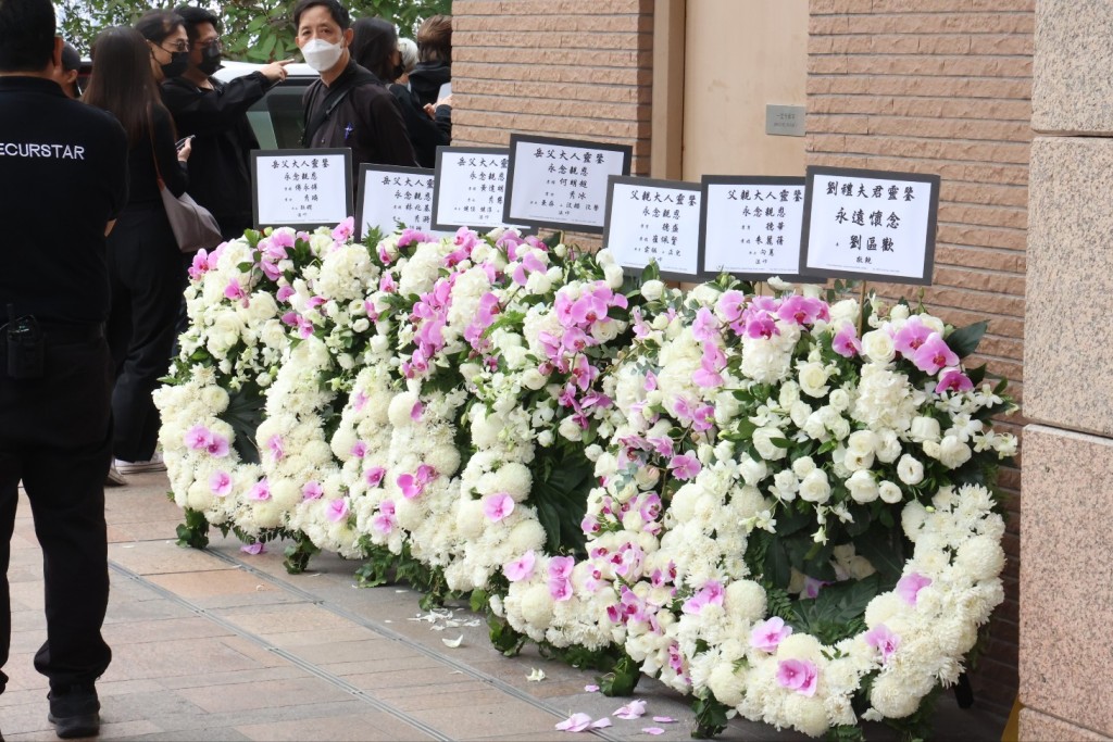 礼堂外摆放了不少花圈，刘德华与太太、女儿致送的花牌上写着「永念亲恩」。