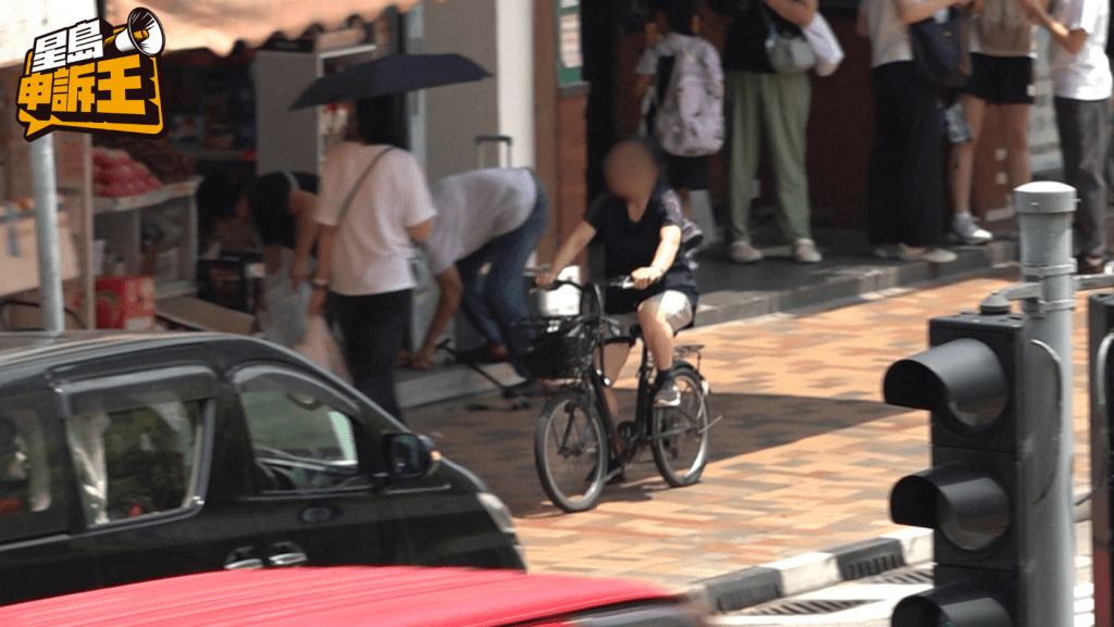 一名女子違規在行人路踩單車。