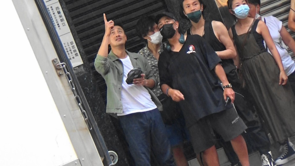 拍了一個避子彈Shot後，雨勢忽然又增強，結果大家又停手匿喺簷蓬下。