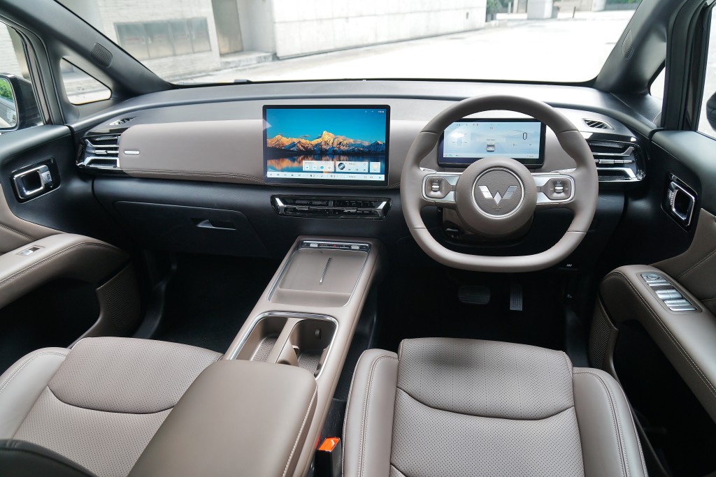 The interior features a modern dashboard with a large central touchscreen display, a digital instrument cluster behind the steering wheel, and a spacious seating arrangement in a seven-seat MPV with a 2+2+3 configuration, highlighting the electric Wuling Darion EV with a sleek design.