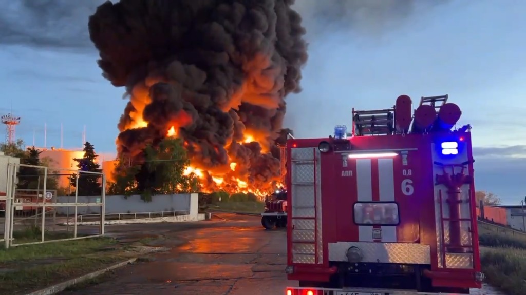 濃煙和火焰從克里米亞儲油廠燃燒的油箱中升起，一輛消防車正駛往現場。AP