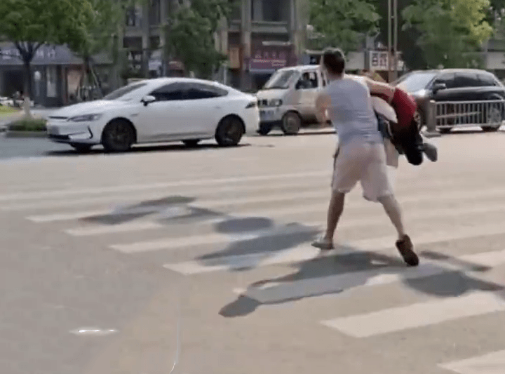 網傳影片顯示，一名男子抱著一堆衣物走出馬路。