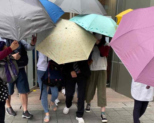 被告在多人掩護下離開法院(中間西裝男)。張旭珊攝