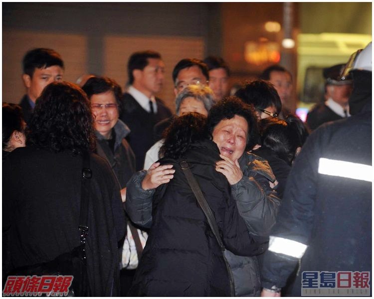 消防隊目楊俊傑英勇殉職，其同袍及家屬在火場外路祭，同袍哀傷，親友相擁痛哭。