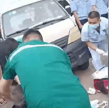 救護人員救治一名坐在地上的傷者。